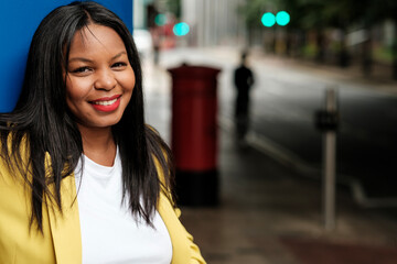 Smiling businesswoman leaning against blue wall in london