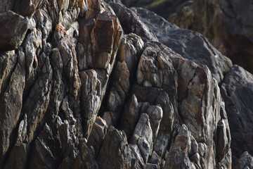 A close-up view of a jagged rock formation with sharp edges and a blend of dark gray and brown...