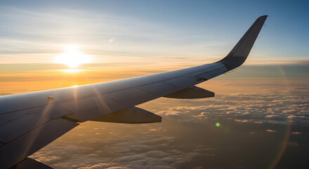 Aerial view of airplane wing during flight at scenic sunset over the clouds landscape