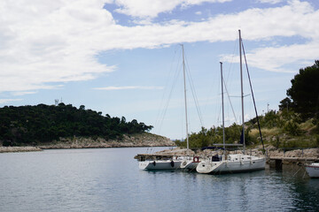 Moored yachts and boats on the pier of the seashore on a sunny day