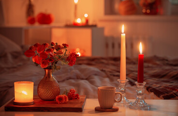 cup of tea and  chrysanthemum in vase with burning candles in bedroom