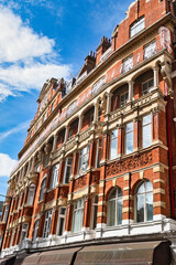 Red brick building with arched windows and decorative elements under blue sky  in London, UK.