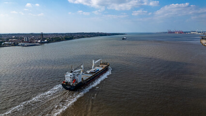 Cargo ship on water with coastal city and port  in Liverpool, UK.
