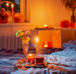 cup of tea and  chrysanthemum in vase with burning candles in bedroom