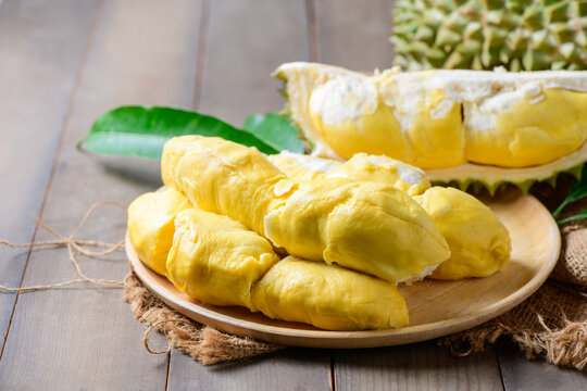 Ripe durian fruit or Durio zibethinus with yellow creamy pulp exposed on wood plate
