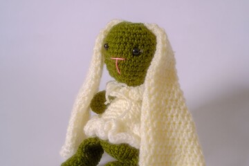 Close-up image shows a green crocheted bunny doll.