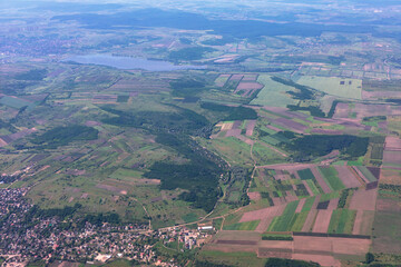 Aerial shot of patchwork of fields and forests surrounding a large lake. Village sits in the foreground, with more settlements visible in the distance