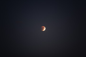 A beautiful lunar eclipse creates a striking reddish hue on the moon, showcasing the wonders of the universe against a clear, dark backdrop. Stargazers admire the celestial phenomenon
