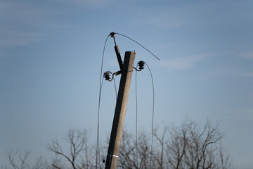 A wooden utility pole stands tall with power lines extending into a clear blue sky. Surrounding trees are bare, indicating late autumn or early winter. The scene captures a quiet rural landscape