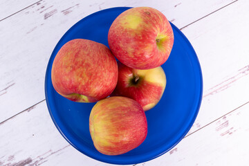 Honeycrisp apples in a blue bowl on white-washed wood surface.