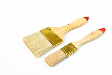 Two wooden handled paintbrushes with red tips and golden ferrules Isolated - on  white background. One brush is larger than the other. 