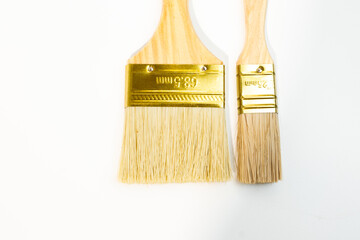 Two wooden handled paintbrushes with red tips and golden ferrules Isolated - on  white background. One brush is larger than the other. 
