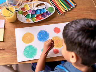 Child painting coloured circles in school. Education concept.