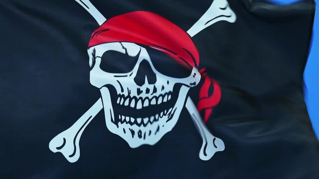 Slow motion video of pirate flag waving on blue background