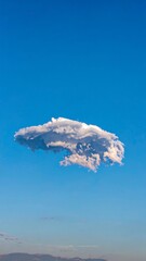 A solitary cloud floats against a vibrant blue sky