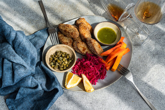 Breaded chicken slices with roasted pumpkin, pickled red cabbage and beetroot (pelustka), capers, traditional sour cherry sauce (tkmemali) and  amber wine on a table