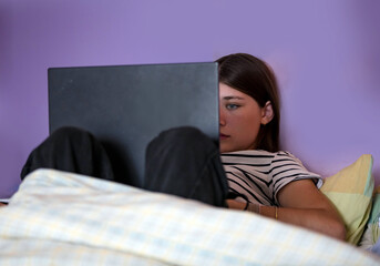 Beautiful young girl working or communicating with her laptop
