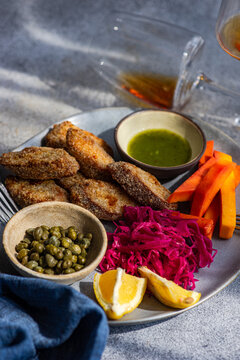 Breaded chicken slices with roasted pumpkin, pickled red cabbage and beetroot (pelustka), capers, traditional sour cherry sauce (tkmemali) and  amber wine on a table