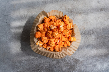 Close-up overhead view of a bowl of homemade cheesy popcorn on a table