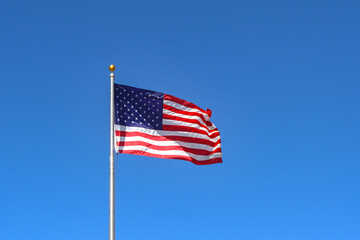 United States of America national flag The Stars and Stripes, isolated against a deep blue sky. Copy space. No people.
