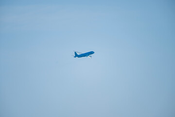A solitary blue airplane glides through a pristine, cloudless sky at cruising altitude.