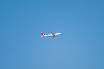 an airplane soars through a vast, cloudless blue sky in mid-flight.