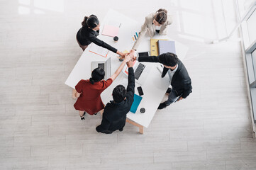 Business team putting hands together in unity during a meeting, symbolizing teamwork, collaboration, partnership, and success in a modern office environment.
