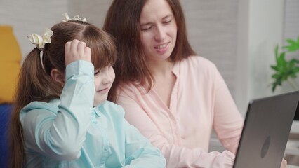 Child girl study at home on computer with their mother. Home schooling, mom daughter, laptop. Family school, daughter schoolgirl does homework at table, teacher helps, teamwork. Happy family education