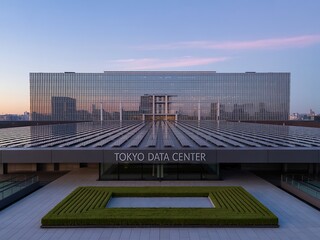 Tokyo data center at dusk with a modern architectural design, showcasing the buildings sleek lines, glass facade, and integration with the urban landscape during the serene evening light