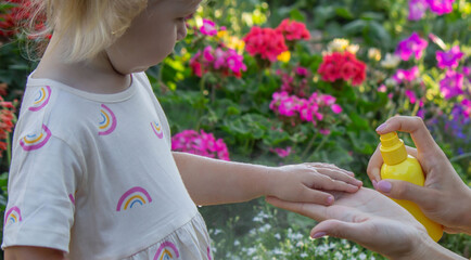 Father applying insect repellent spray to child's hand outdoors. Selective focus