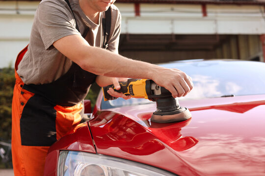 Man polishing car hood with orbital polisher outdoors, closeup - Powered by Adobe
