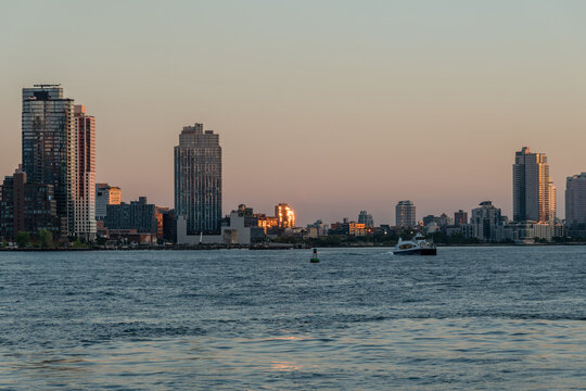 Sun reflecting in the building windows at sunset in Brooklyn along the East River shore, viewed from across the river on Manhattan, New York City