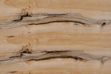 Close-up of a light wooden surface showing natural grain, knots, and cracks in the texture. Ideal for backgrounds, design, or material reference.