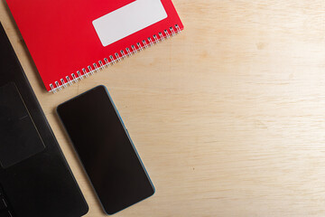 Office workspace with notebook, smartphone, and laptop on wooden desk, business and Education concept, top view background.