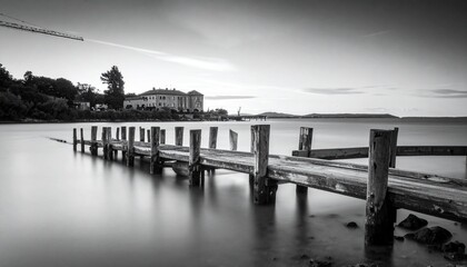 Black and White Pier on Calm Water with Buildings in Background.