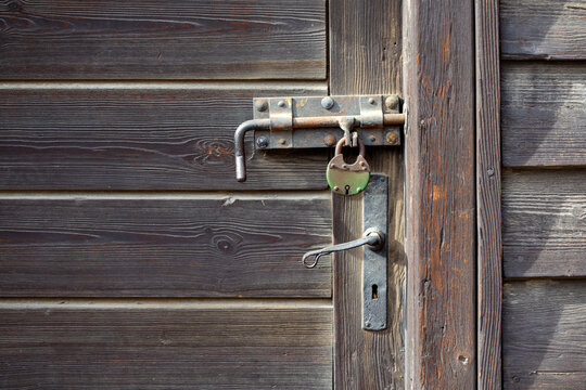 Rustic weathered wooden door with old metal lock and handle.