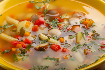Delicious homemade soup with sausages, colorful peppers and fresh herbs