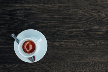 Hot espresso in a white ceramic cup placed on dark wooden table background with roasted aroma caffeine and lifestyle mood