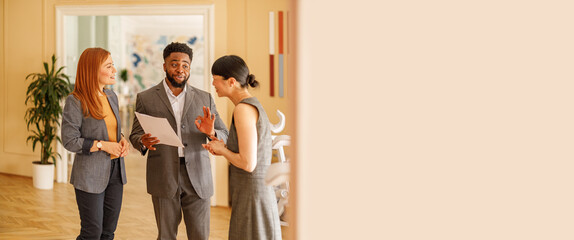 Male lawyer holding documents and explaining contract details to female teammates in collaborative...
