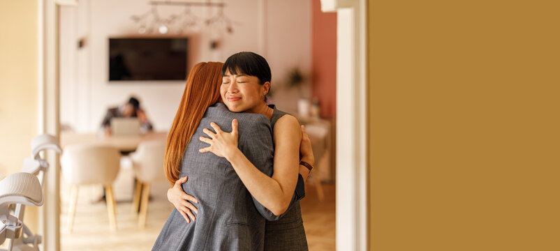 Professional woman shares a welcome embrace with teammate in office showing appreciation and encouragement