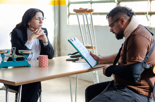 Young female lawyer assist a injured man with legal problem. Man reading document. Compensation for work or car accident. Legal concept. Social Worker.