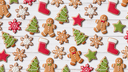 Christmas gingerbread cookies in festive shapes like trees, snowflakes, and stars on white wooden background. Holiday baking concept.