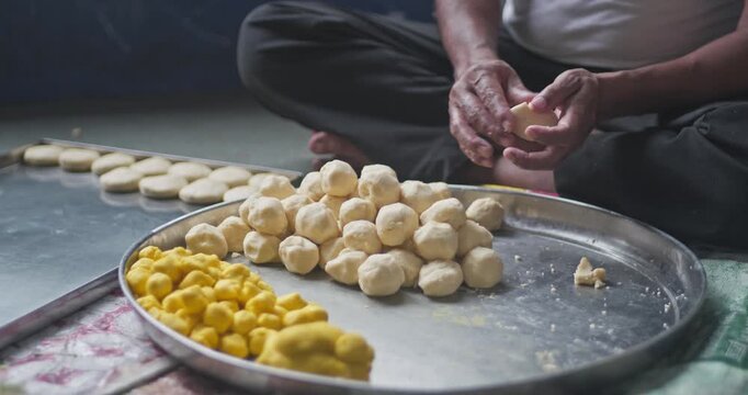 Cinematic shot of hands rolling creamy malai peda into perfect spheres, highlighting rich Indian dessert preparation and festive sweets