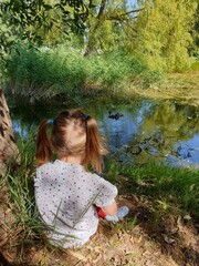Small girl sitting by pond