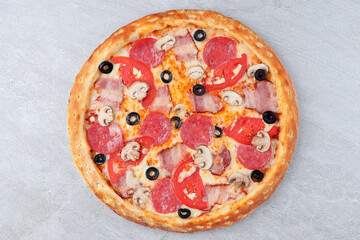 Pizza with Bacon, Pepperoni, Mushrooms, Tomato Slices, Black Olives and Melted Cheese on Stone Background