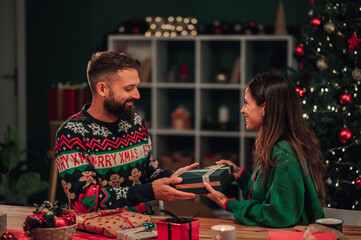 Fototapeta premium Couple exchanging christmas gifts at home