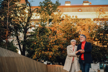 Happy senior couple walking and smiling in autumn city park
