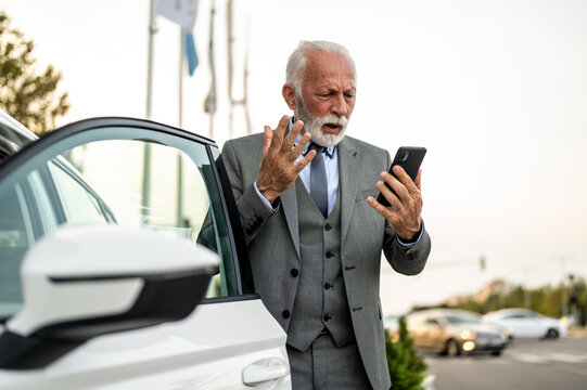 Frustrated senior businessman getting angry reading bad news on mobile phone near car - Powered by Adobe