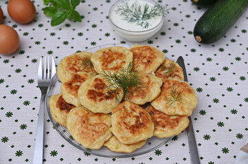 still life with delicious zucchini pancakes and greens on the table