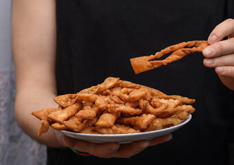 Delicious faworki for Fat Thursday, a man holding a plate of fatty snacks